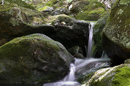 waterfalls on green rocky terrain during daytime thumbnail