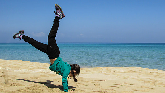 girl in green jacket and black jeans on seashore under blue sky thumbnail