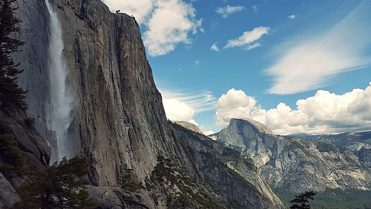 falls and rock mountains under clear blue and white sky thumbnail