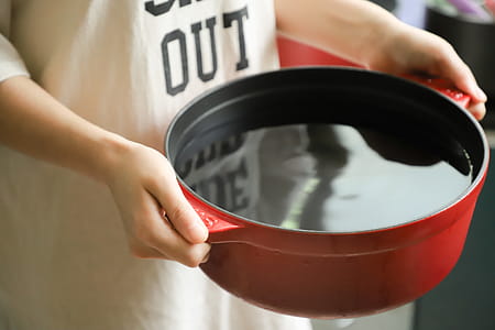 Person Holding Red Pot Filled with Water thumbnail