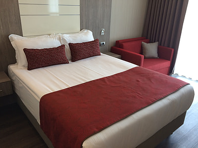 white bed sheet beside red armchair thumbnail