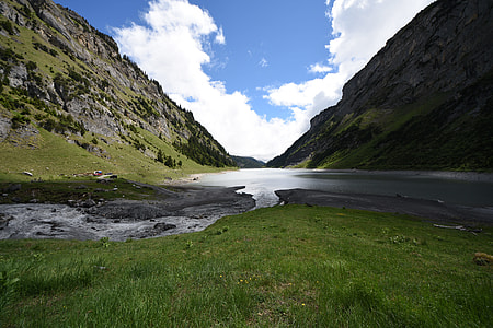 landscape photo of calm water between mountains under cloudy day thumbnail