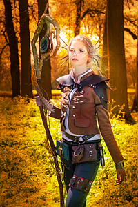 woman wearing brown coat holding brown staff surrounded trees during daytime thumbnail