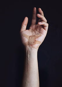 person wearing brown band aid on left palm thumbnail