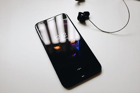 black smartphone turned on beside black earbuds thumbnail
