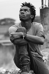 grayscale photo of man sitting on concrete surface thumbnail