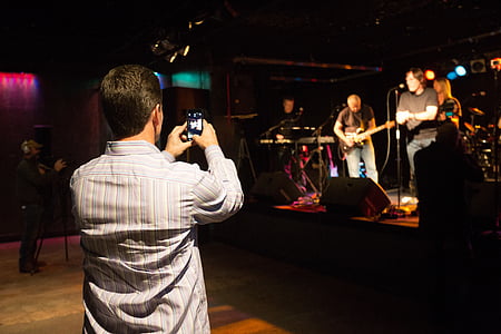 man taking photo of band on stage thumbnail