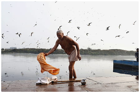 topless man standing beside body of water during daytime thumbnail
