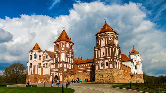 people walking near white and brown castle under cloudy sky during daytime thumbnail