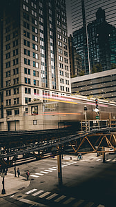timelapse photography of train passing near buildings thumbnail