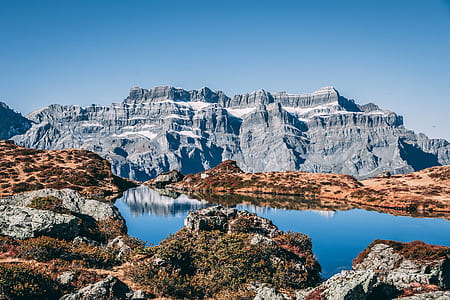 landscape photo of gray rock mountain near body of water during daytime thumbnail