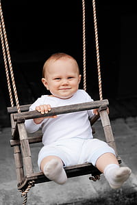 baby sitting on swing chair during daytime thumbnail