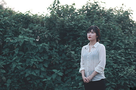 standing woman beside green leaf plants thumbnail
