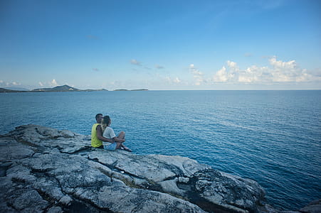Man and Woman Sitting Near Body of Water thumbnail