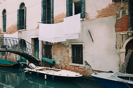 white boat on body of water beside concrete building thumbnail