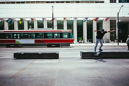A young Caucasian skateboarder in action near a city building with a tram in the background thumbnail