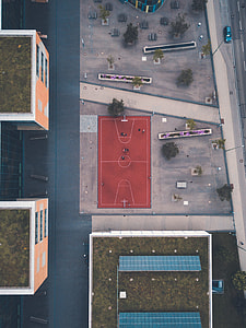 aerial view photography of red basketball court near orange concrete builting at daytime thumbnail