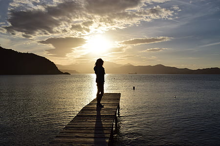 silhouette of person on brown wooden dock during twilight thumbnail
