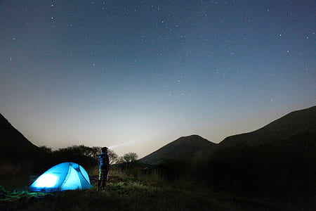 man standing near blue camping tent thumbnail