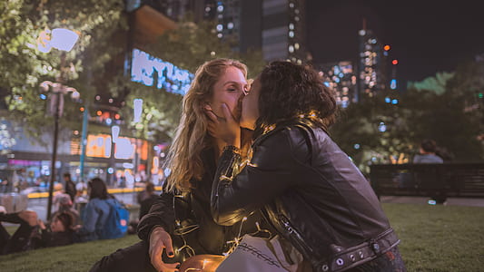 two woman kissing on grass field thumbnail