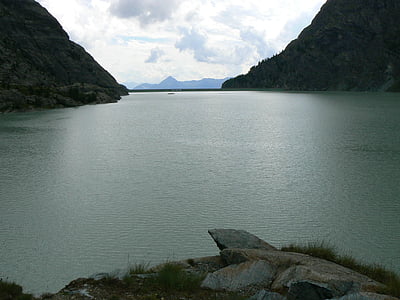 calm body of water surround with mountain during daytime thumbnail