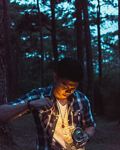 man holding string lights inside jar standing in forest thumbnail