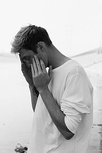 grayscale photography of man holding his face thumbnail
