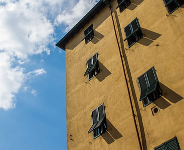 worm's-eye view photography of brown house under cloudy sky thumbnail