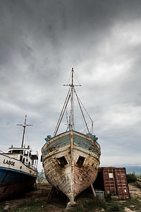 brown and gray abandoned boat near cargo trailer during daytime thumbnail