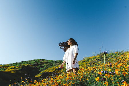 woman standing in yellow flower field during daytime thumbnail