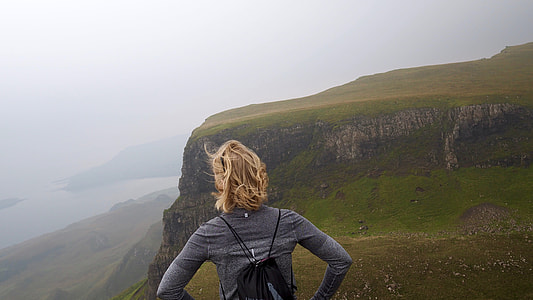 woman standing on mountain facing cloudy skies thumbnail