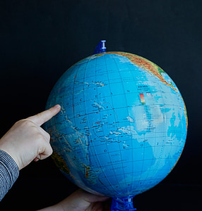 person pointing on Pacific Ocean of desk globe thumbnail