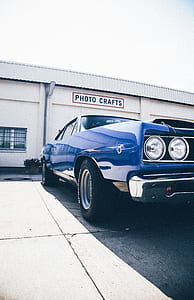 classic blue coupe parked near Photo Crafts building during daytime thumbnail