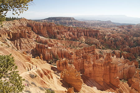several people walking on hill near rock formations thumbnail