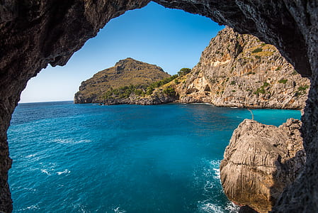 closeup photography of rock cave and blue sea thumbnail