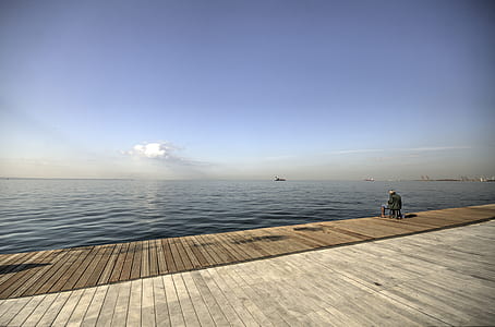 person sitting on platform overlooking the sea thumbnail