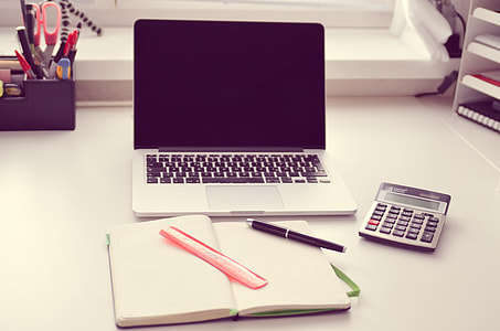 MacBook Pro beside gray and black calculator on white wooden table thumbnail