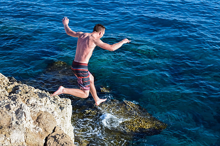 man in red and black shorts jumping on water during dayrmne thumbnail
