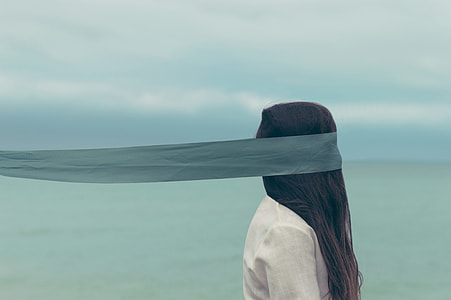 woman in white top with grey blindfold standing near body of water thumbnail