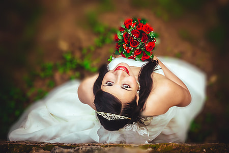 shallow depth of fields photography of woman wearing wedding dress while holding bouquet of roses thumbnail