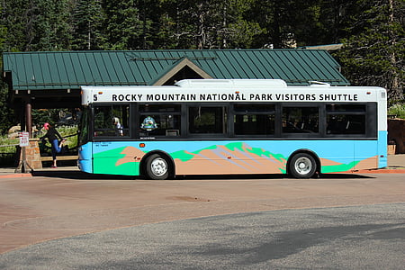 white and blue Rocky Mountain National Park Visitors Shuttle bus near green wooden shed thumbnail