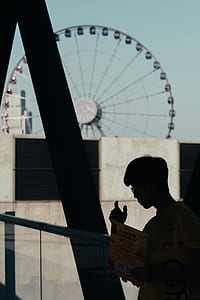 boy holding book while standing near railing thumbnail
