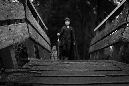 grayscale photo of man walking on bridge thumbnail