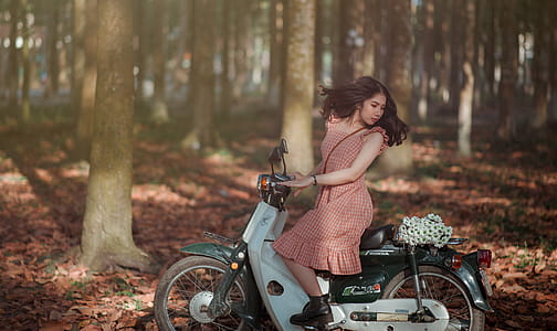 Woman Riding Black and White Motor Scooter in Jungle thumbnail