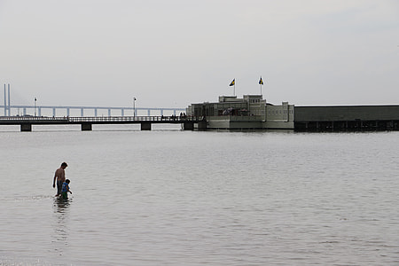 man walking at the sea near a bridge thumbnail