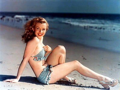 woman wearing black-and-white striped bikini sitting on seashore thumbnail