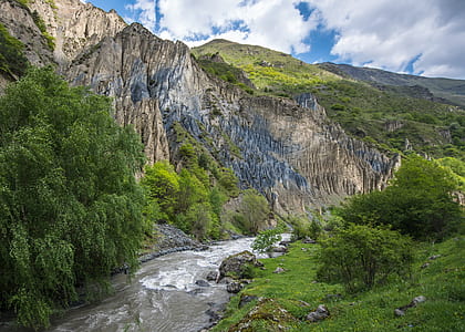 river between cliff and trees at daytime thumbnail