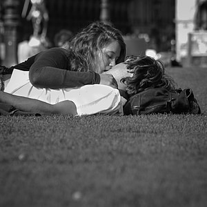 grayscale photo of man and woman kissing on field of grass thumbnail
