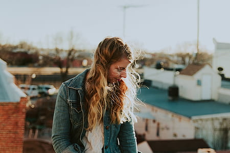 standing woman wearing blue button-up jacket during daytime thumbnail