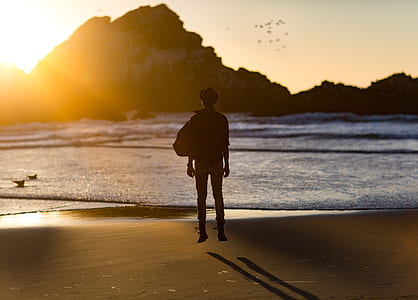 silhouette of man near seashore in front of mountain at daytime thumbnail